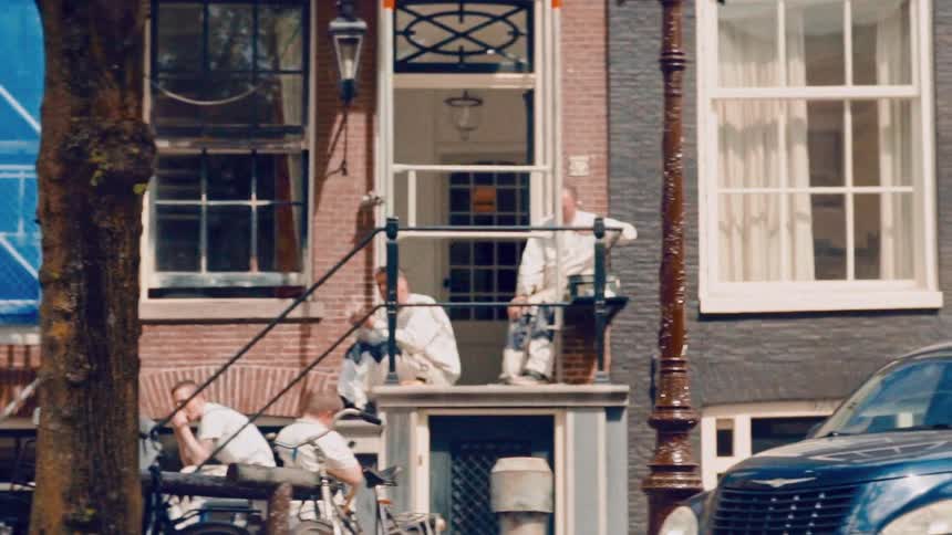 Construction workers dressed in white overalls take a break on the front stoop of a brick townhouse on a city street