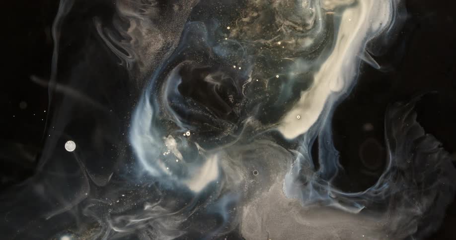 Ethereal clouds of shimmering white and silver ink swirl slowly in a dark liquid, creating a cosmic, galaxy-like effect