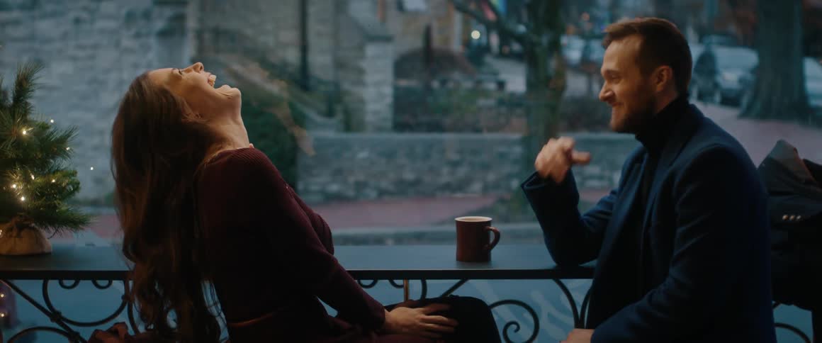A slow motion shot of a young woman laughing hysterically while on a date with her boyfriend at a cafe