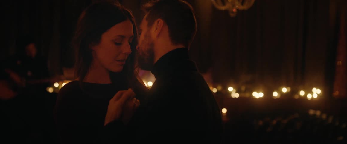 An affectionate couple shares a slow, intimate dance in a dimly lit, romantic room