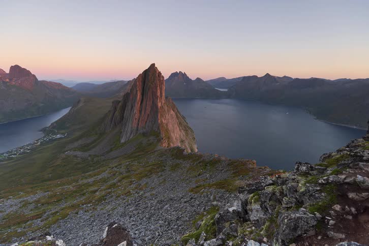 Stunning day-to-night timelapse captures the sunset over the dramatic Segla mountain and a Norwegian fjord as a coastal village begins to glow