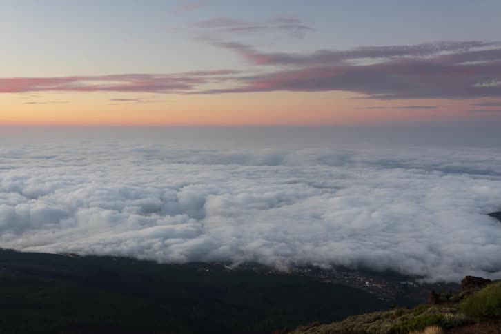 A breathtaking high-angle view of a sea of clouds covering a valley during a colorful sunset