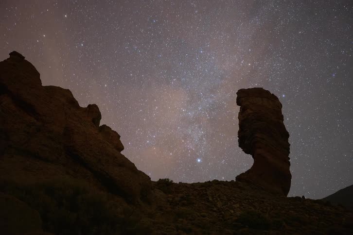 A breathtaking timelapse of the Milky Way galaxy moving across the starry night sky behind a prominent silhouetted rock formation