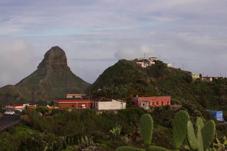 A timelapse of morning fog and clouds clearing to reveal a small village nestled among lush green volcanic mountains