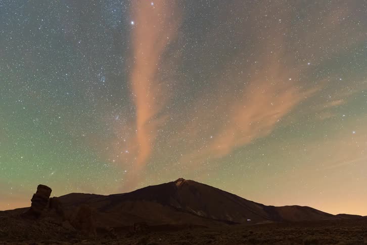 A stunning night-to-day time-lapse shows the Milky Way and stars rotating above a volcanic mountain landscape as clouds drift by