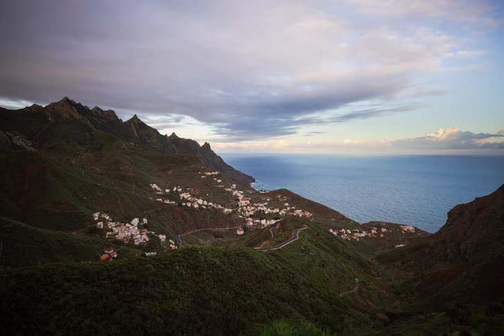 A dramatic time-lapse of a picturesque village nestled in the green mountains of a rugged coastline at sunset