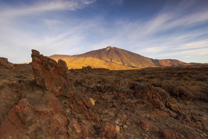 A stunning time-lapse shows the sun's golden light moving across the volcanic peak of Mount Teide, casting long shadows over the rocky landscape