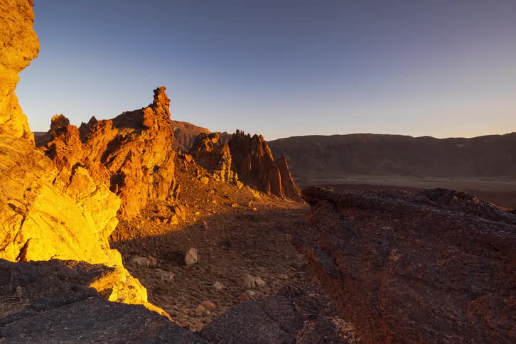 Golden hour sunset timelapse over a rugged volcanic landscape, as shadows move across the valley floor