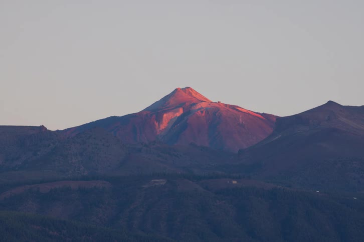 A stunning timelapse captures the golden light of sunrise illuminating the majestic peak of a volcanic mountain