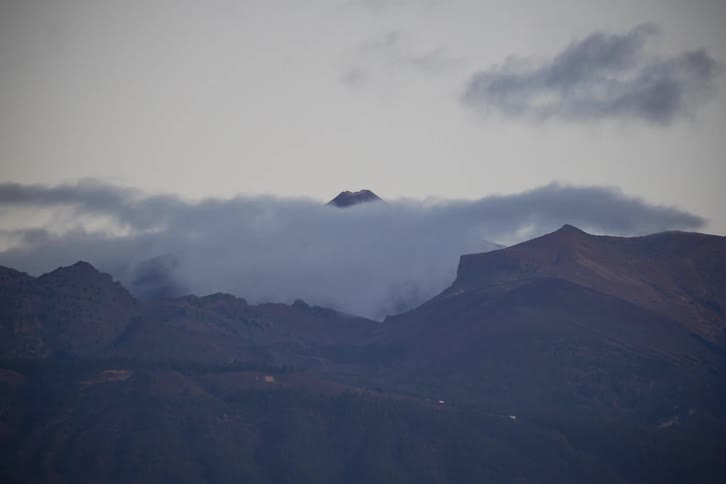 A stunning timelapse shows thick clouds swirling and dissipating around a majestic volcanic peak as the sunrise casts a warm, golden glow on the mountain