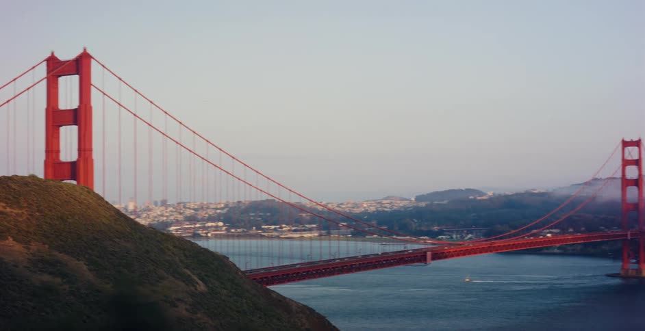 A scenic panning shot of the iconic Golden Gate Bridge reveals the San Francisco skyline and bay as fog rolls over the distant hills