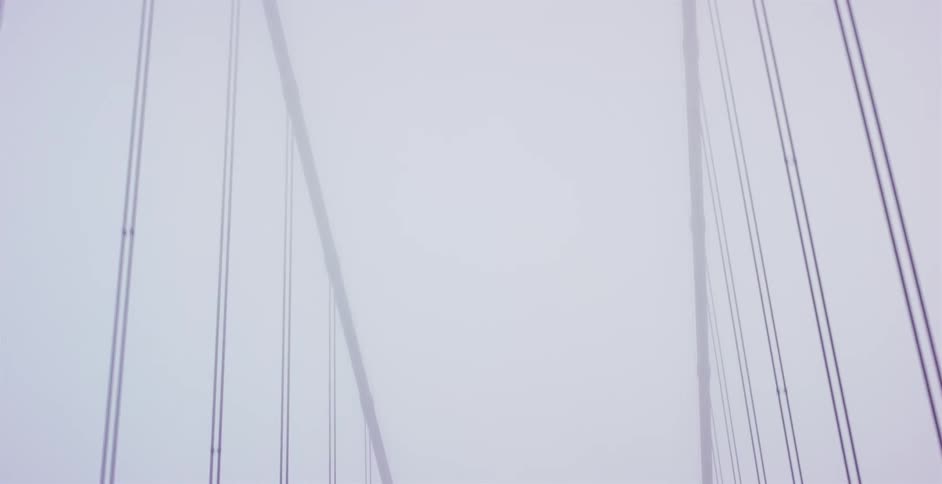 Abstract low-angle view of suspension bridge cables disappearing into a dense, white fog