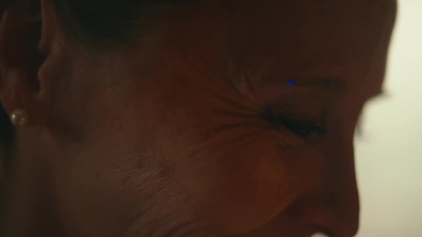 An intimate, soft-focus macro shot captures the beautiful wrinkles around a woman's smiling eye, celebrating natural aging