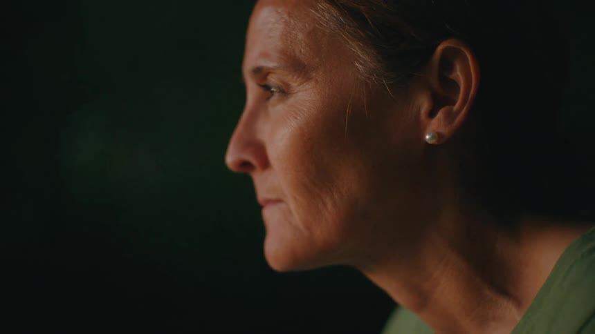 Intimate slow-motion profile shot of a mature woman closing her eyes in a moment of quiet contemplation