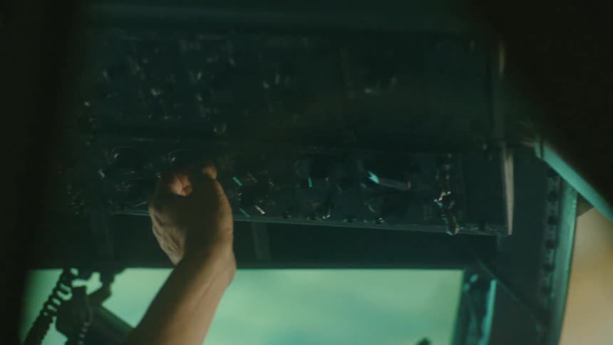 From inside the cockpit, a pilot's hand expertly adjusts switches on the overhead instrument panel