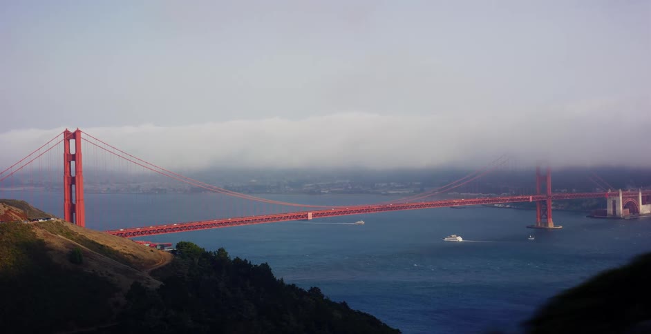 A parallax view from a moving vehicle reveals the Golden Gate Bridge and San Francisco Bay under a layer of low-lying fog