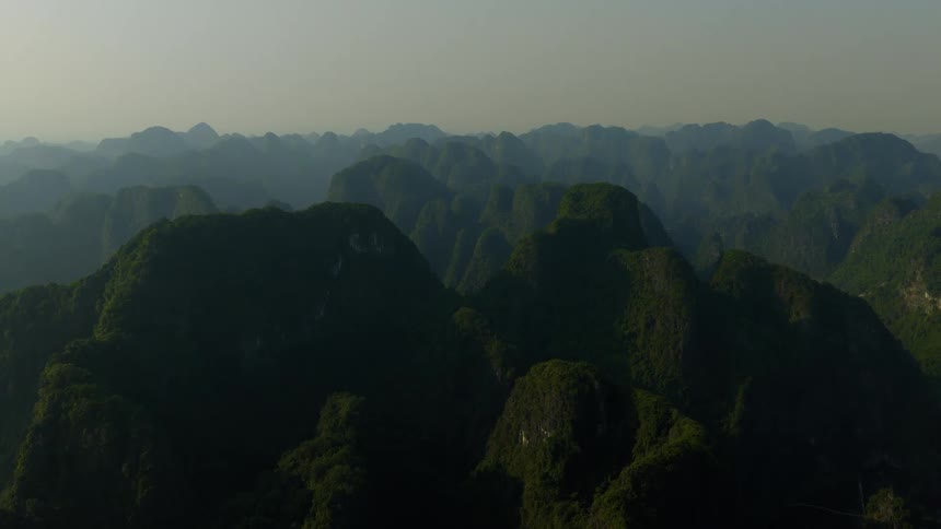 A majestic and serene static shot captures a vast, hazy mountain range covered in lush green jungle