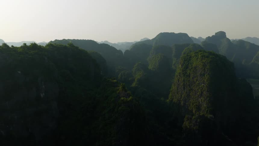 A majestic static aerial view of a lush green mountain range and valley shrouded in haze