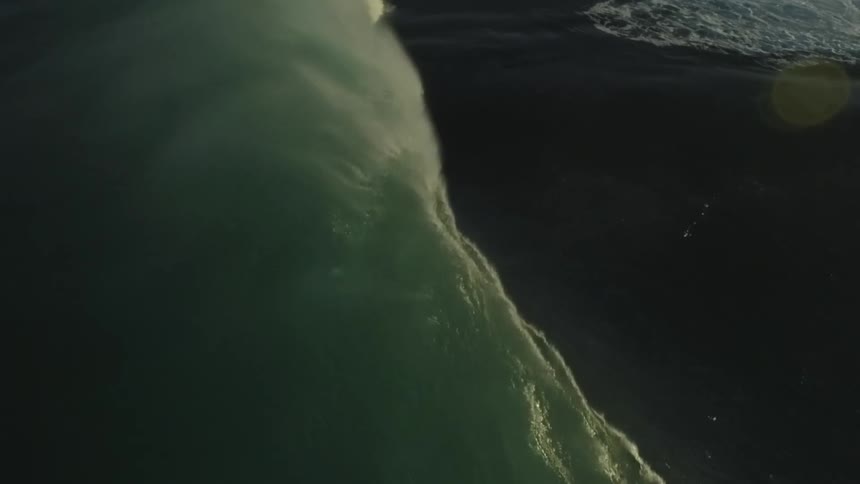 A dramatic slow motion close-up of a massive ocean wave forming and cresting in the dark sea