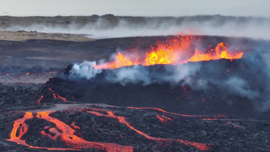 Dramatic slow motion footage shows a volcanic fissure eruption with lava fountains and flowing rivers of molten rock
