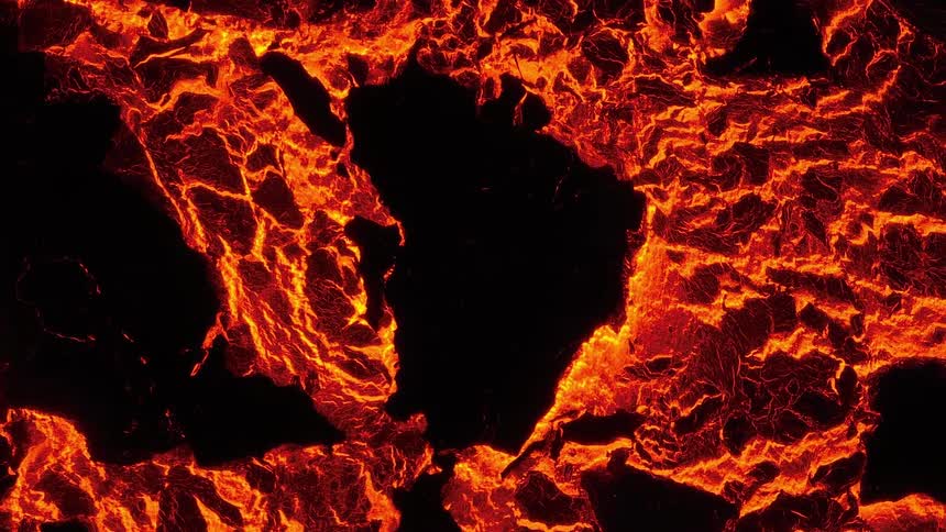 An abstract overhead view shows the intense power of a fiery molten lava field as it slowly cools and cracks
