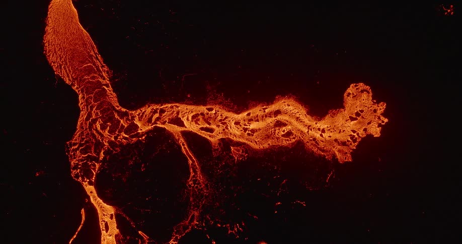 An incredible top-down aerial view shows a glowing river of molten lava flowing and solidifying against a black background