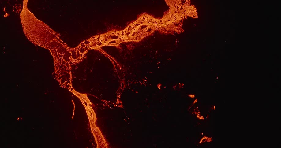 An abstract top-down aerial view of a glowing, molten lava river slowly flowing and cooling against a pitch-black background