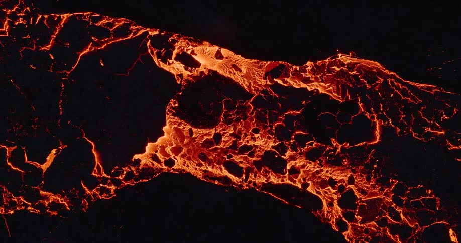 A fiery river of molten lava glows intensely as it flows and cools into dark volcanic rock