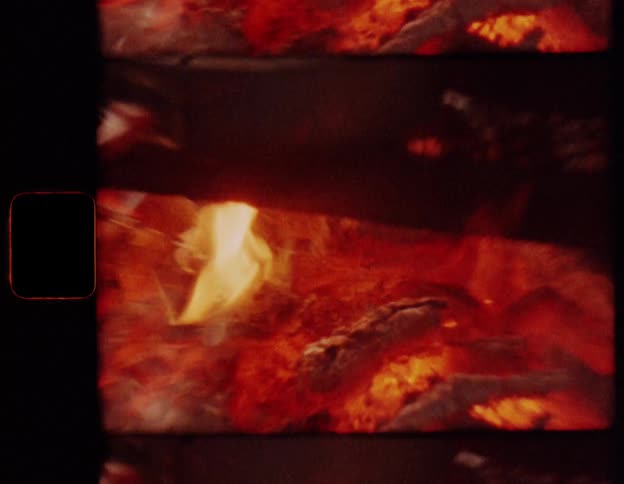 Vintage footage shows a meal being prepared in a pot and kettle over a rustic campfire in the woods