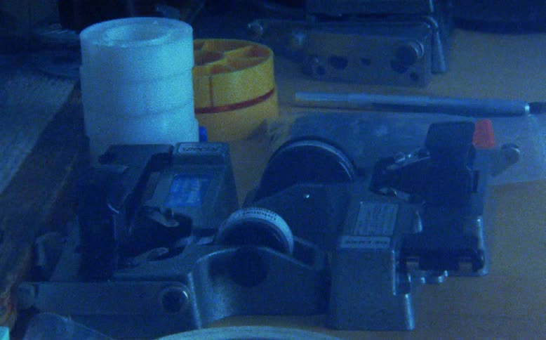 Light moves across a vintage film splicer and other analog editing equipment sitting on a desk