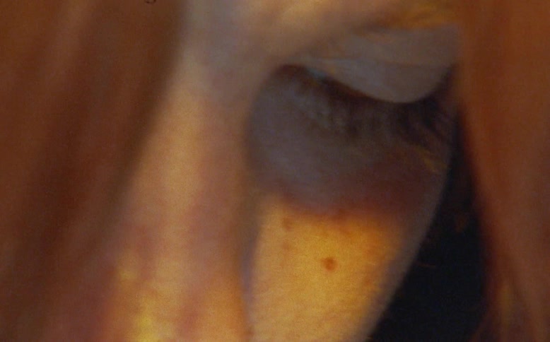 A moody, artistic close-up reveals the pensive face of a young woman with vibrant red hair