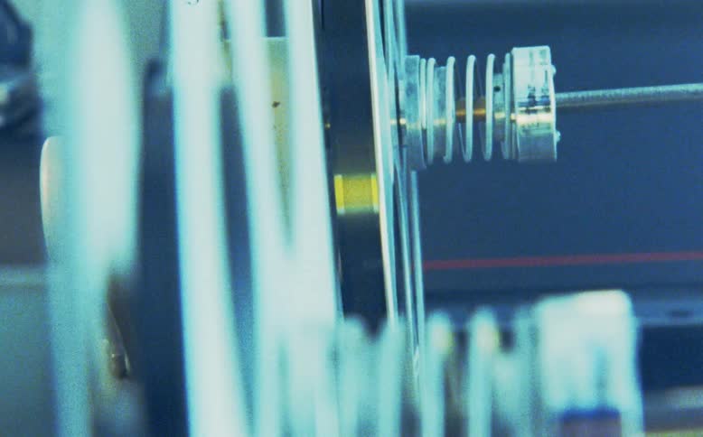 Extreme close-up side view of a vintage 35mm film reel spinning on a projector
