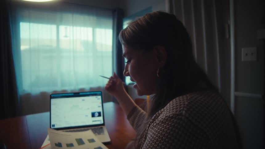 A man and woman enthusiastically review their financial portfolio at home, analyzing upward trending charts on a laptop