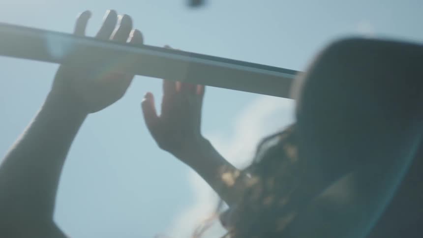 A woman holds her hands out the open window of a moving vehicle