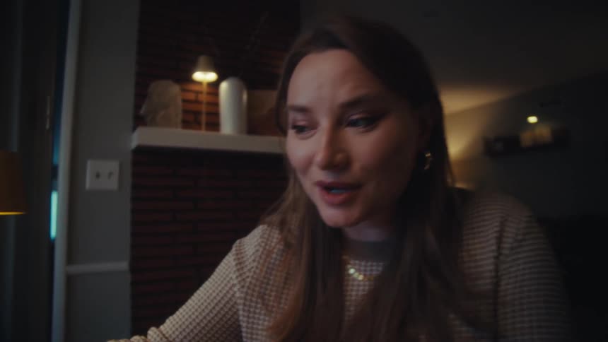 A woman uses a stylus to explain a rising cryptocurrency chart on a laptop to a man in their home