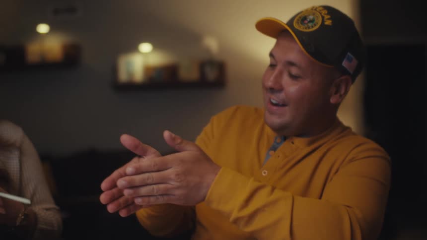 A slow motion close-up of a military veteran man enthusiastically talking to a woman in their cozy home at night