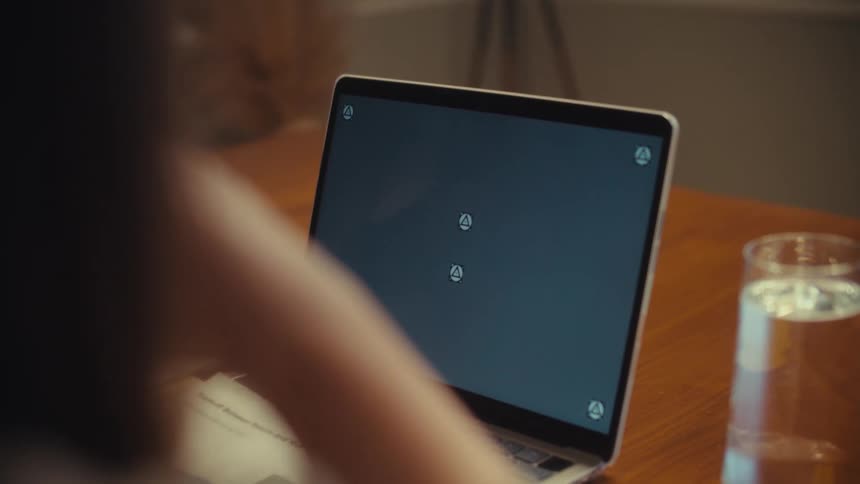 Close up over the shoulder shot of two colleagues in a meeting analyzing charts and pointing at a laptop screen with tracking markers