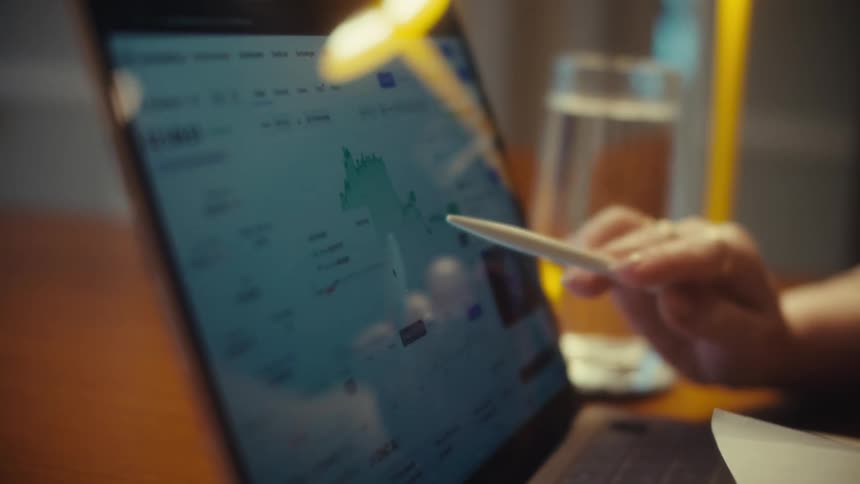 A close-up of a businesswoman analyzing a stock market chart on a touchscreen laptop with a stylus
