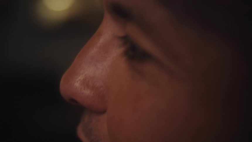 An intimate and moody slow-motion extreme close-up of a man's eye and face