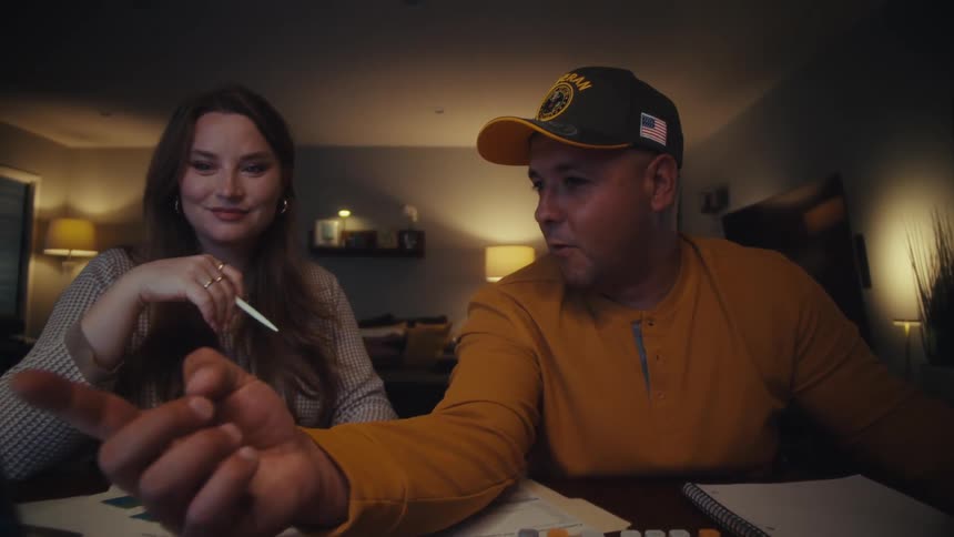A couple collaborates on their budget at night, using a laptop, calculator, and paperwork to manage their finances at home