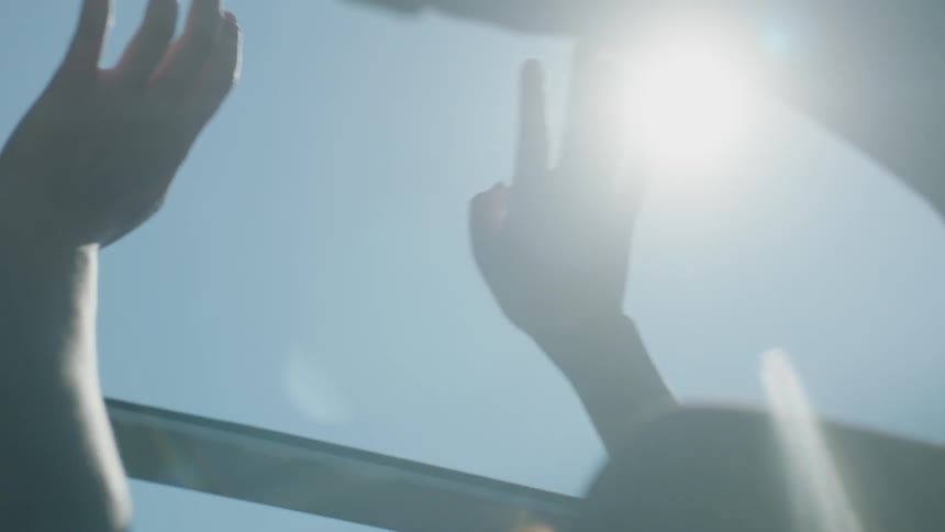 Woman passenger holding hands out open roof of vehicle feeling the wind