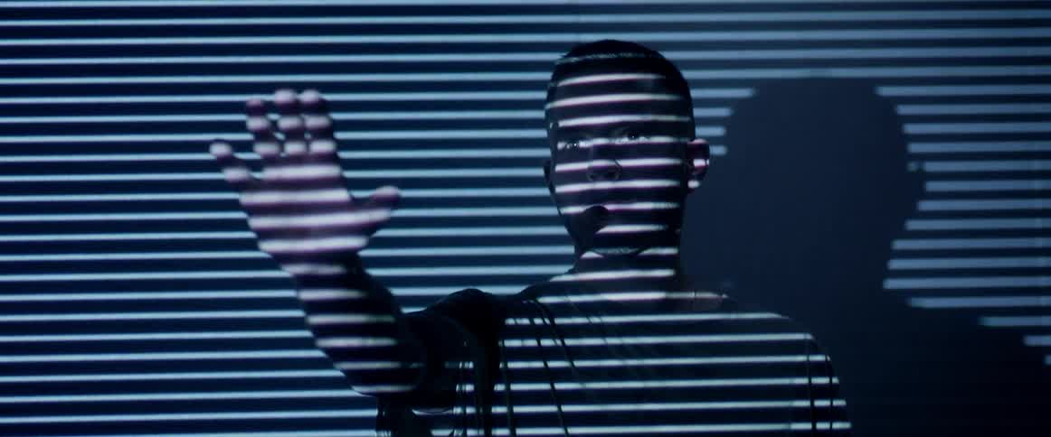 Man standing in lined light holds his arm up