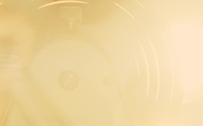An editor operates a vintage film editing flatbed machine, manually rewinding the film reel