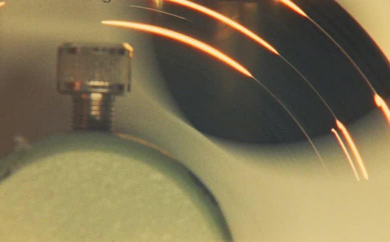A hazy, dreamlike close-up of a hand starting a vintage fan, with its blades spinning in the warm light
