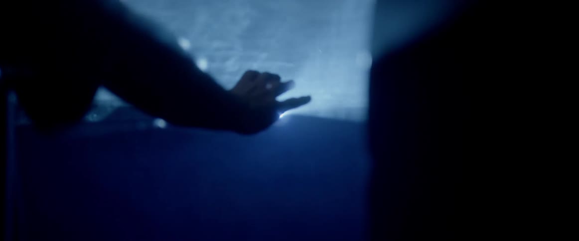 Person puts hand up as strobe beams shine through