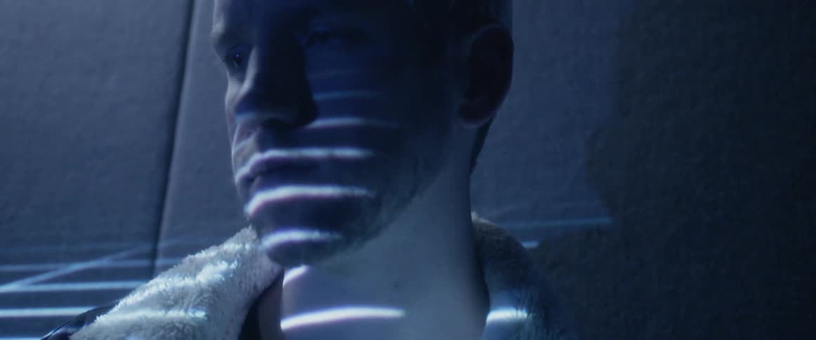 Guy stands against wall in a dark room