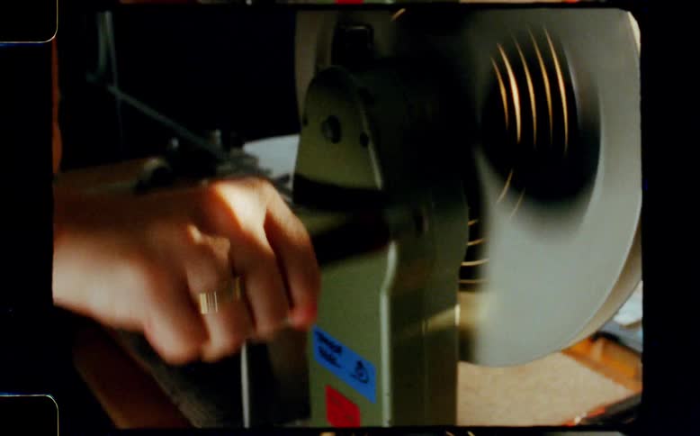 Vintage 8mm footage captures a close-up of a hand turning the crank of a film rewinder