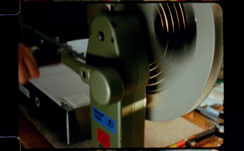 A person rewinds film on a vintage manual film rewinder, captured on authentic super 8 footage