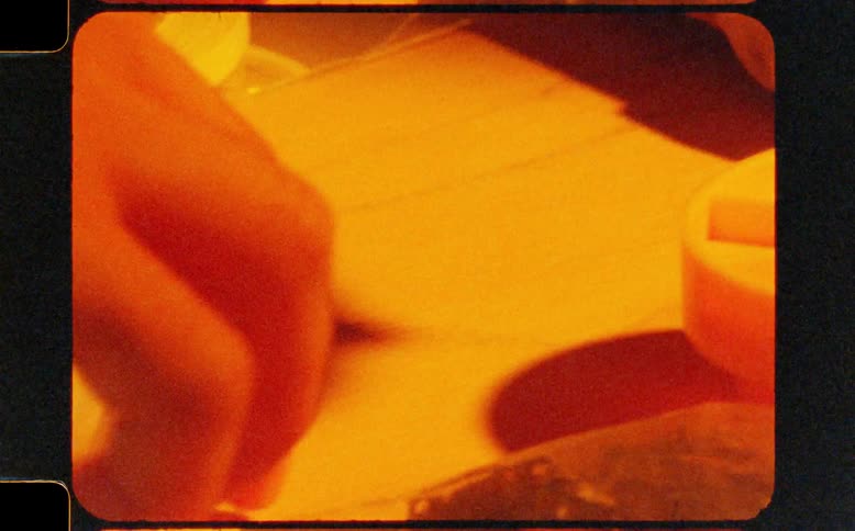 Vintage 8mm footage shows a close-up of hands arranging industrial plastic components