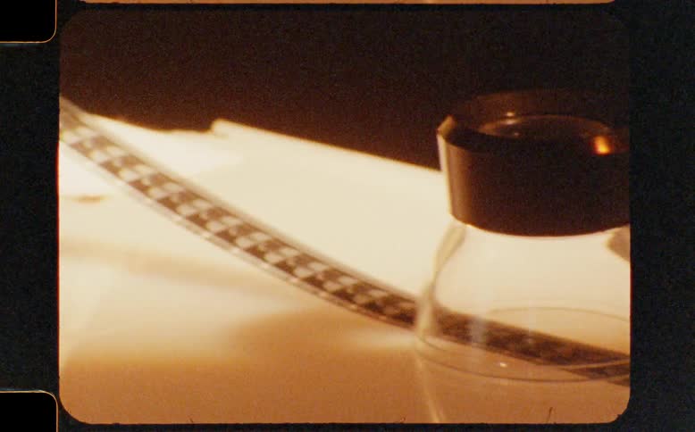 A vintage macro shot captures the intricate details of an 8mm film strip being wound onto a reel in a darkroom